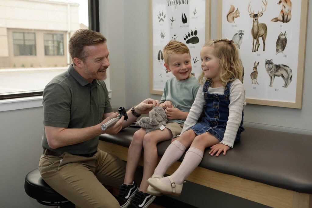 Doctor Talking To Siblings On Examination Couch